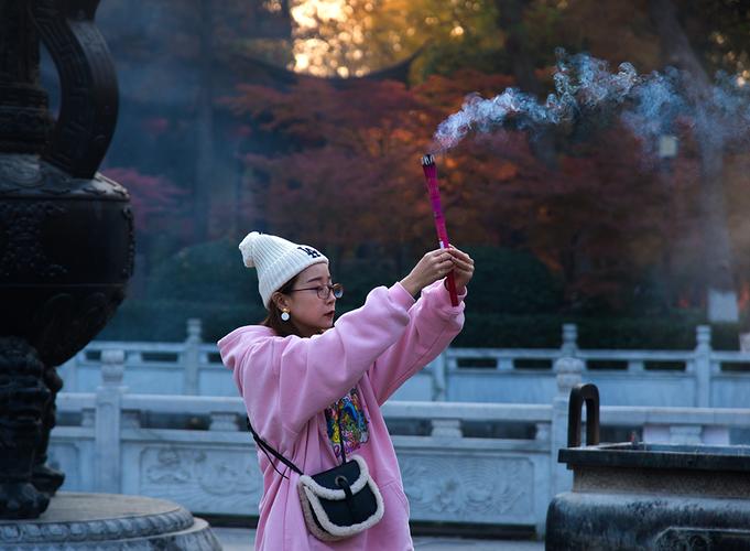 2023年12月8日拍摄于南京栖霞山栖霞寺香炉前,年轻的女孩虔诚地在