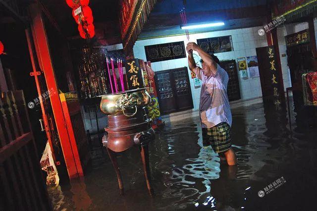 印尼中部爪哇岛暴雨导致水灾,一名华人在大水淹没的寺庙中上香