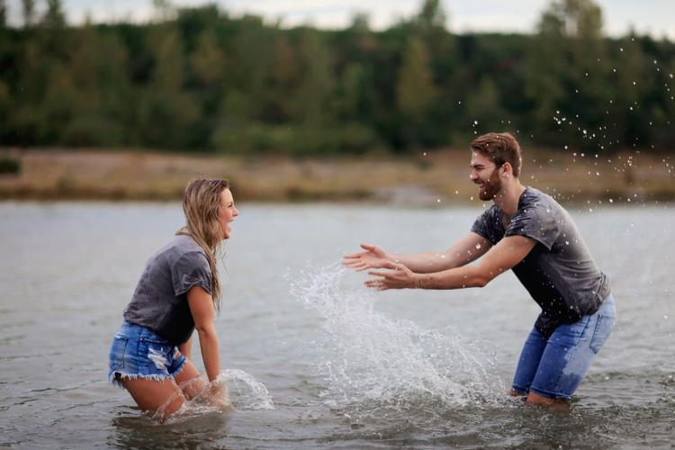 一个男人站在水里抱着一个笑的女人
